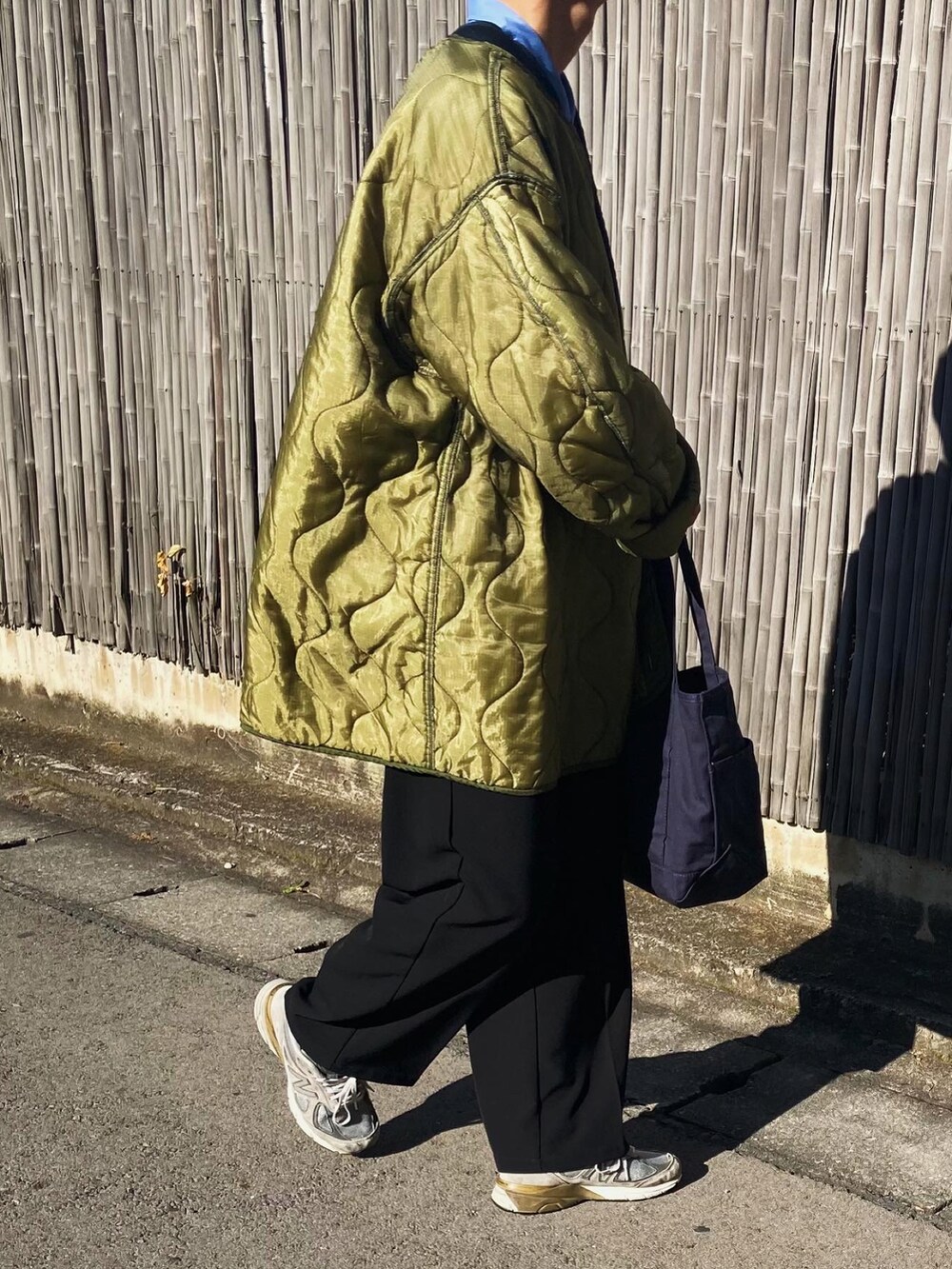 ブラック系のスラックス、グレー系のスニーカー、ブルー系のトートバッグを着用したメンズの秋コーディネートの3枚目の写真