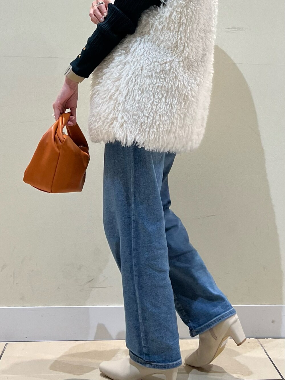 グリーン系のニット/セーター、ブルー系のデニムパンツ、イエロー系のショルダーバッグを着用したレディースの秋コーディネートの3枚目の写真