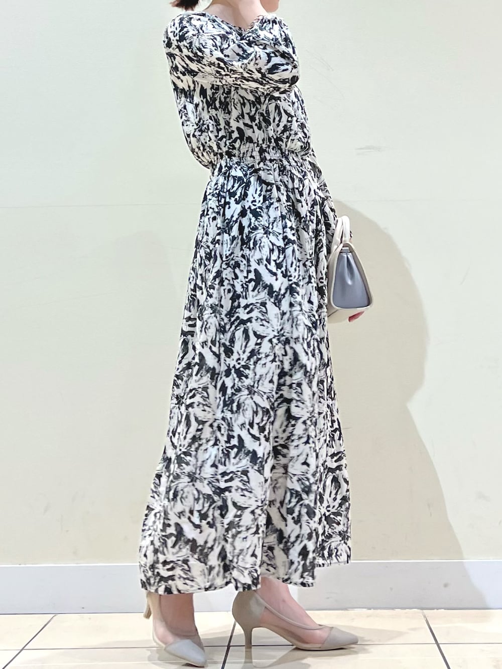 ベージュ系のパンプス、ブラック系のワンピース、ホワイト系のショルダーバッグを着用したレディースの冬コーディネートの2枚目の写真