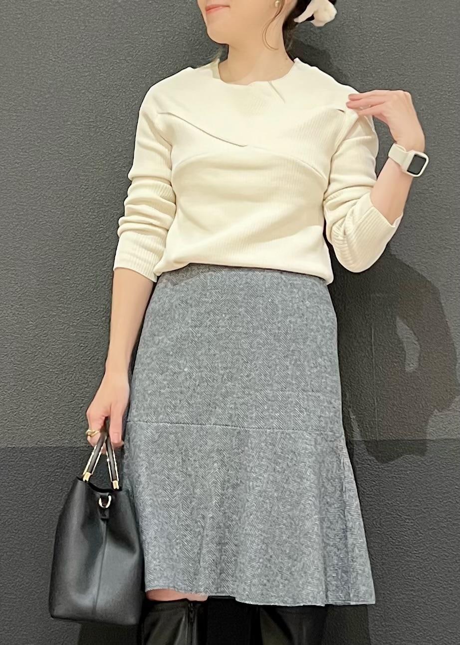 グレー系のスカート、ブラック系のショルダーバッグ、ホワイト系のニット/セーターを着用したレディースの秋コーディネートの2枚目の写真