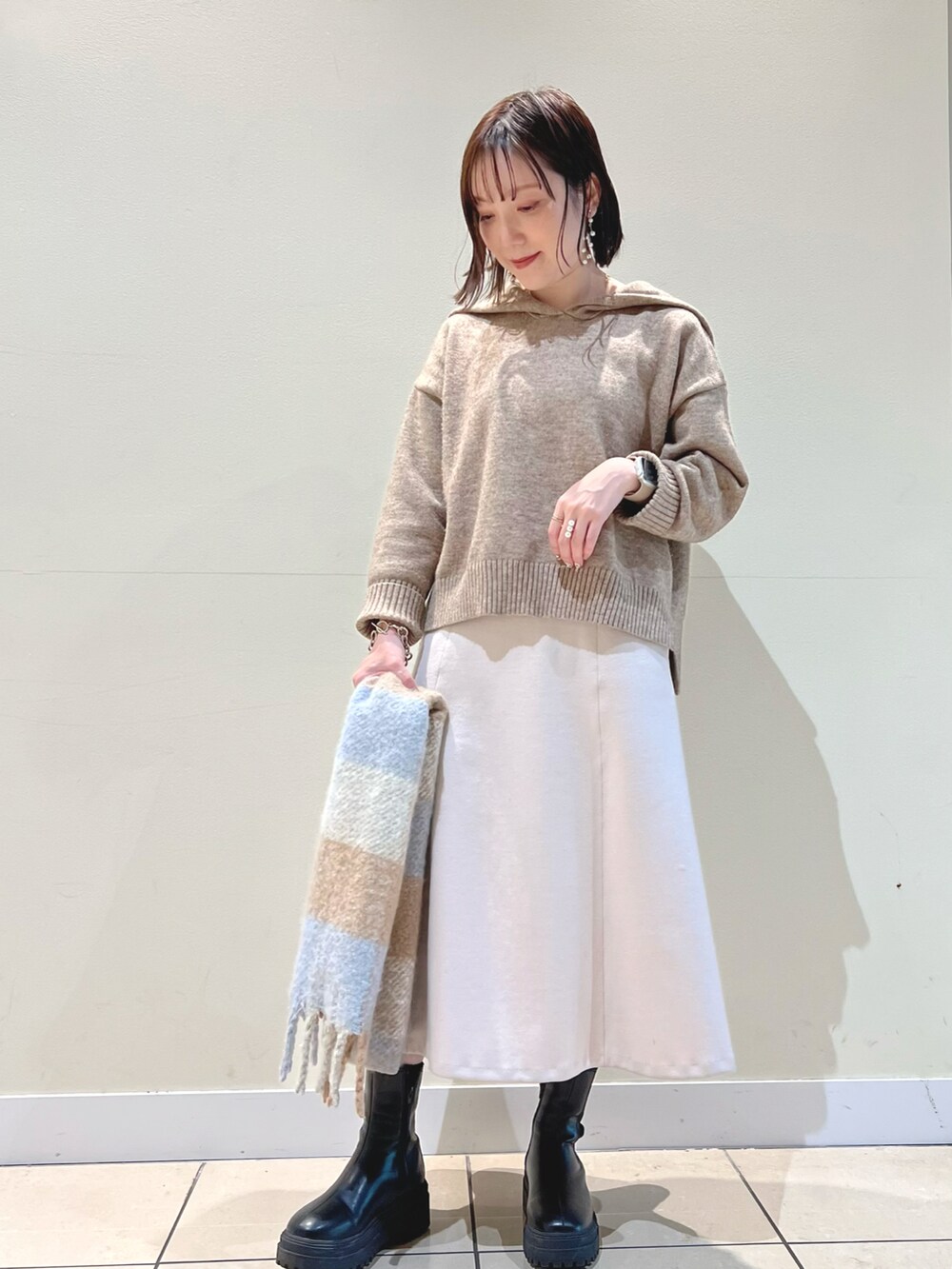 ベージュ系のニット/セーター、ピンク系のスカート、ブルー系のストール/ショールを着用したレディースの冬コーディネートの3枚目の写真