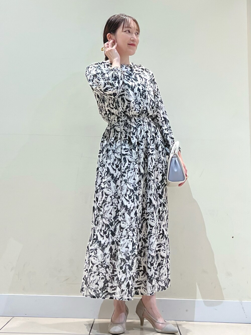 ベージュ系のパンプス、ブラック系のワンピース、ホワイト系のショルダーバッグを着用したレディースの冬コーディネートの3枚目の写真