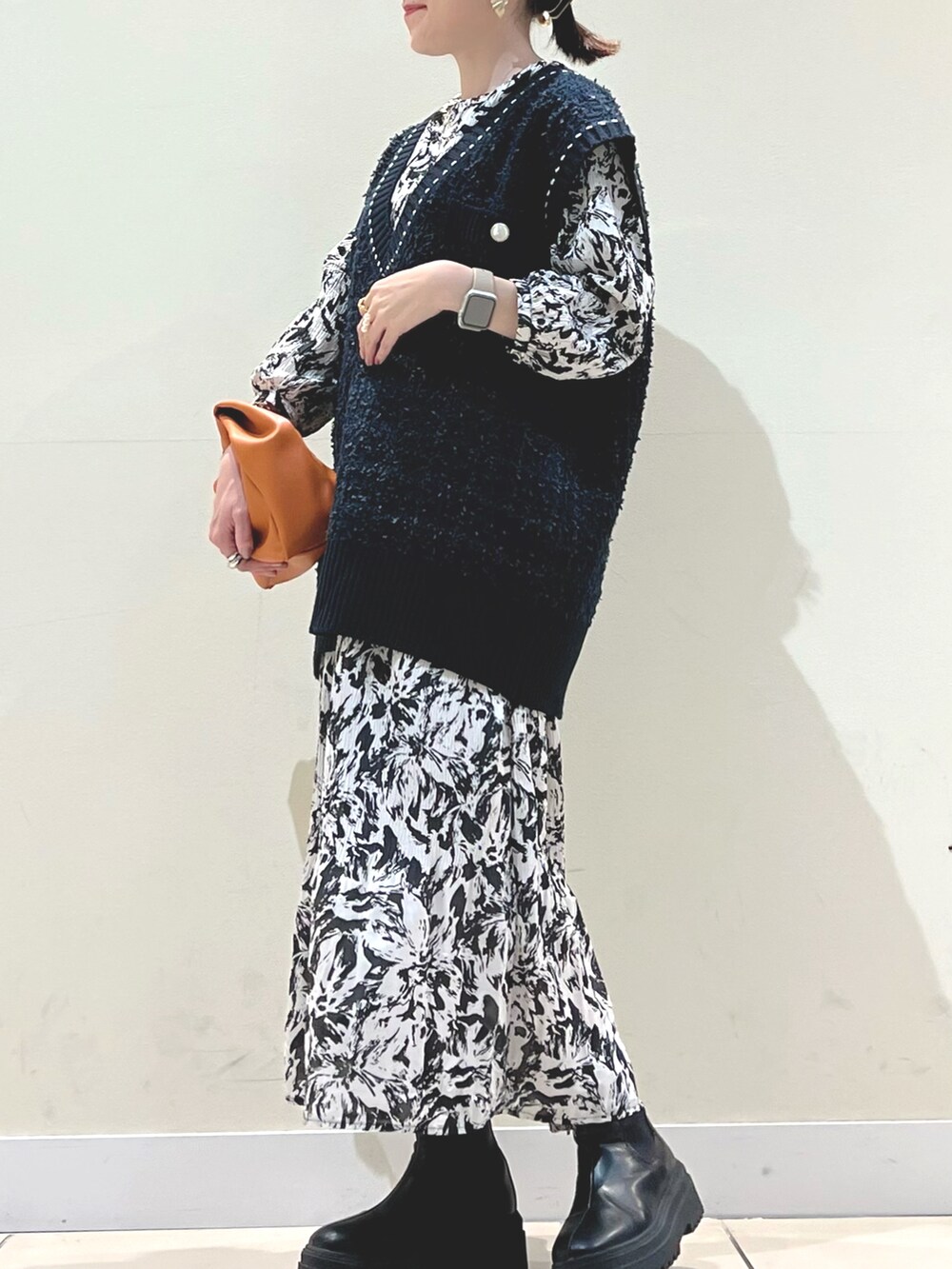 イエロー系のショルダーバッグ、ブルー系のベスト、ブラック系のワンピースを着用したレディースの秋コーディネートの3枚目の写真