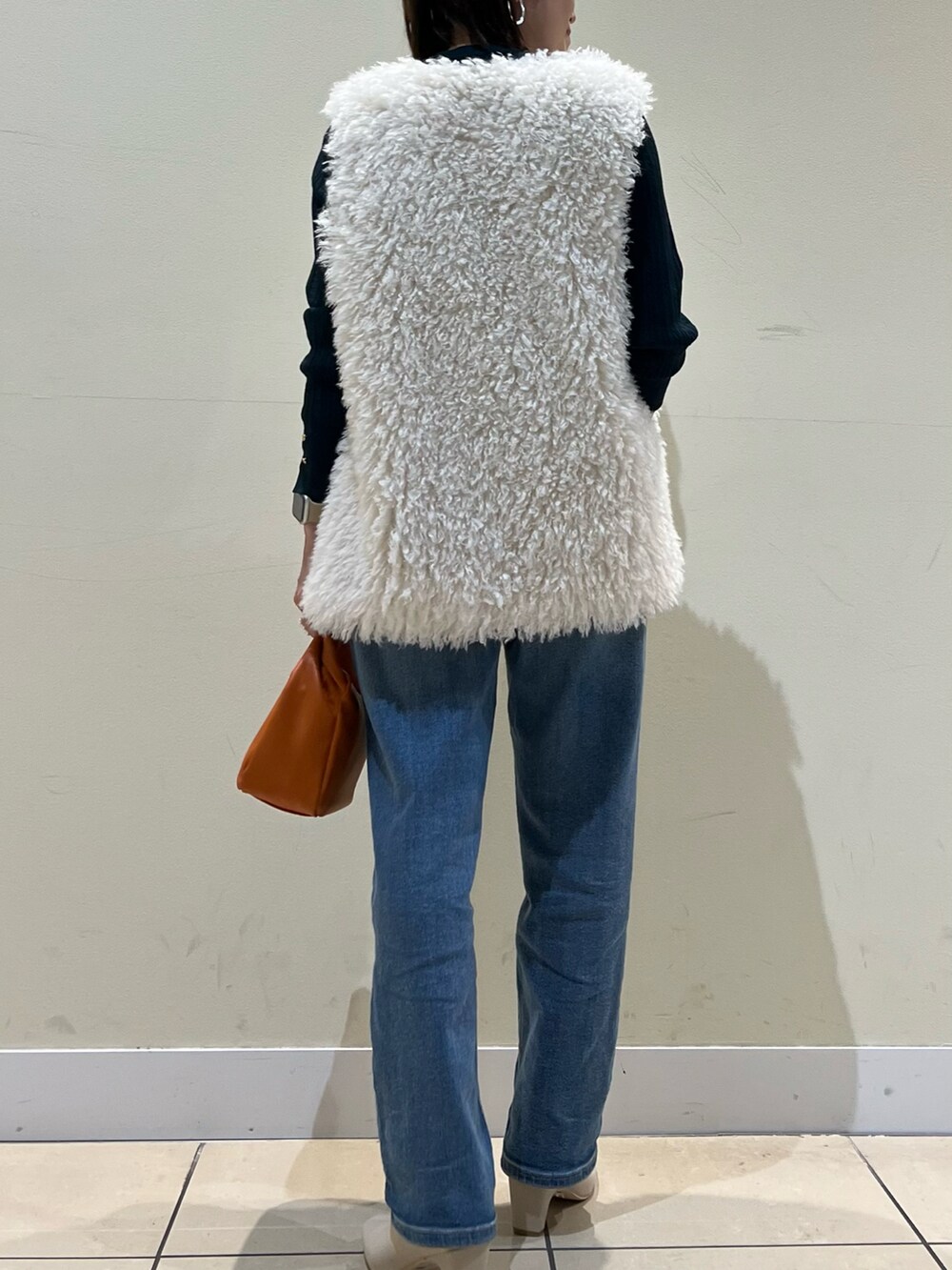 グリーン系のニット/セーター、ブルー系のデニムパンツ、イエロー系のショルダーバッグを着用したレディースの秋コーディネートの2枚目の写真