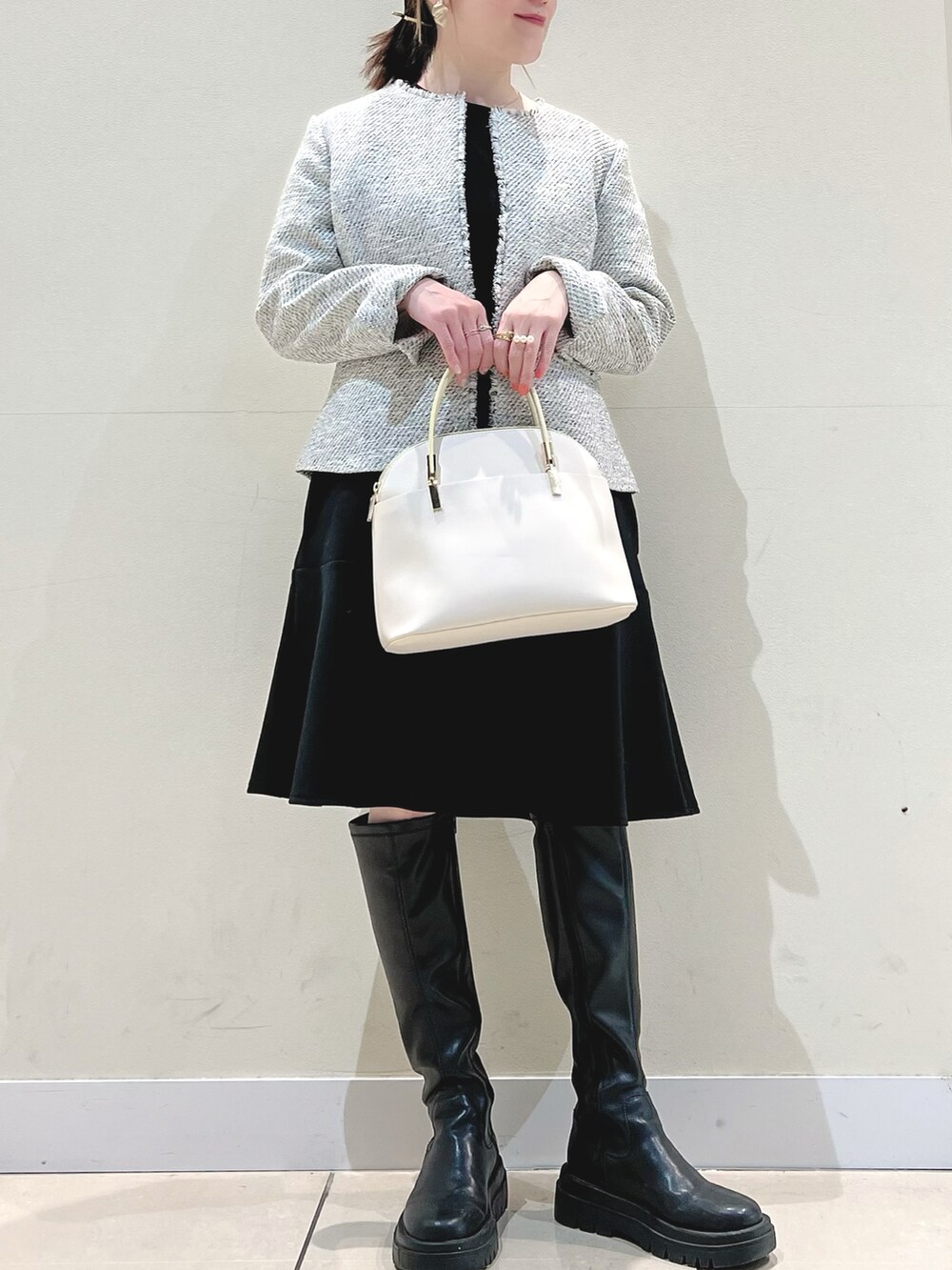 ホワイト系のノーカラージャケット、ブラック系のワンピース、ホワイト系のショルダーバッグを着用したレディースの冬コーディネートの3枚目の写真