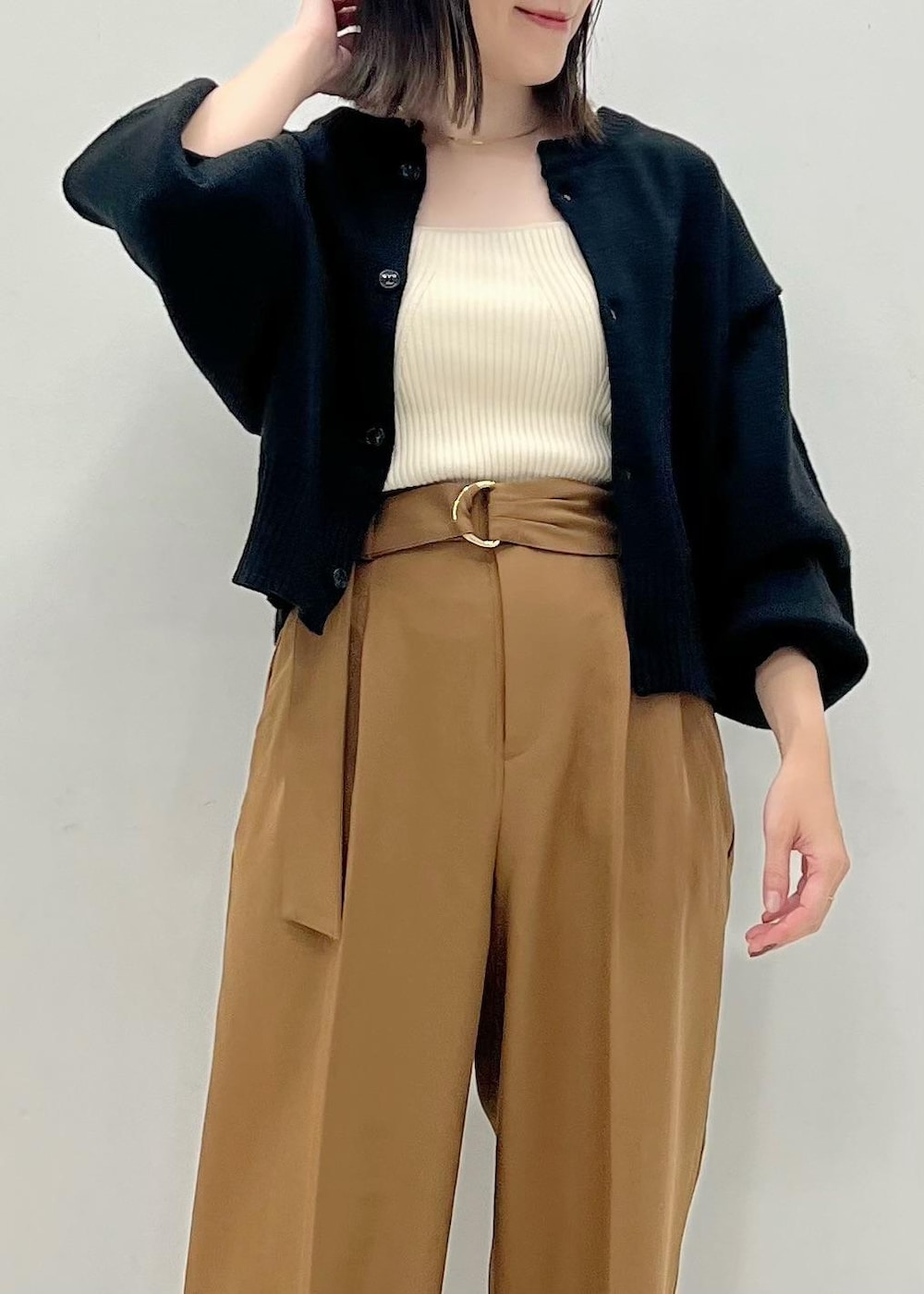 ブラック系のカーディガン/ボレロ、ホワイト系のベスト、ブラウン系のブーツを着用したレディースの秋コーディネートの3枚目の写真