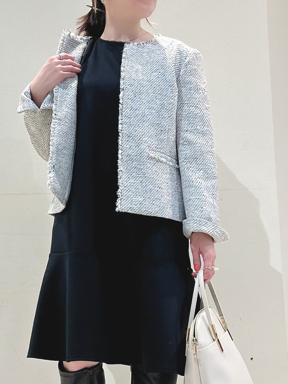 ホワイト系のノーカラージャケット、ブラック系のワンピース、ホワイト系のショルダーバッグを着用したレディースの冬コーディネートの2枚目の写真