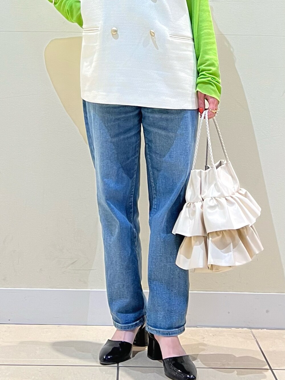 ホワイト系のベスト、グリーン系のTシャツ/カットソー、ブラック系のパンプスを着用したレディースの春コーディネートの2枚目の写真