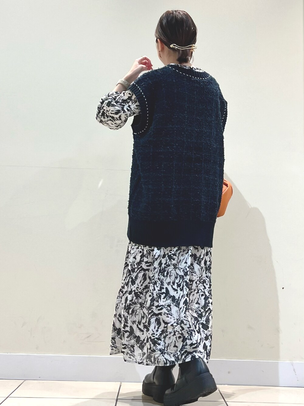 イエロー系のショルダーバッグ、ブルー系のベスト、ブラック系のワンピースを着用したレディースの秋コーディネートの4枚目の写真