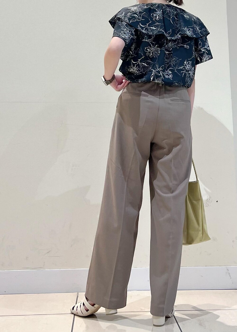 イエロー系のトートバッグ、ホワイト系のサンダル、ブラウン系のその他パンツを着用したレディースの夏コーディネートの3枚目の写真