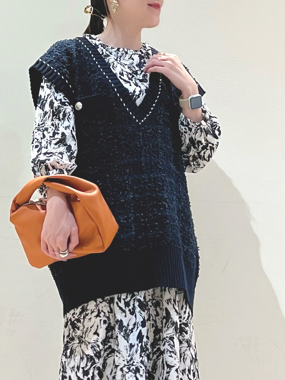 イエロー系のショルダーバッグ、ブルー系のベスト、ブラック系のワンピースを着用したレディースの秋コーディネートの5枚目の写真