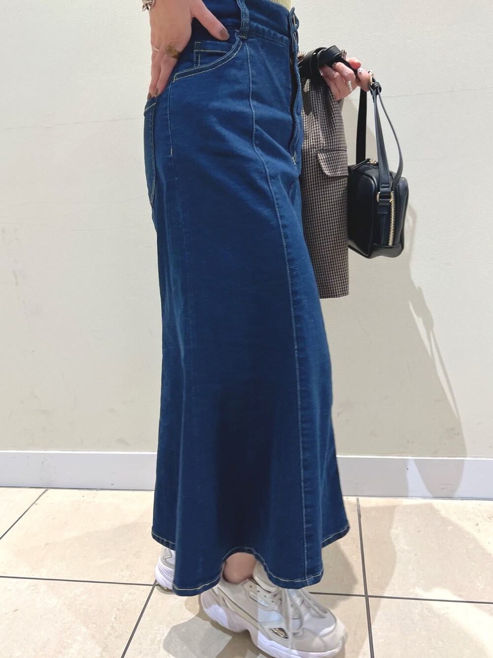 ブラック系のショルダーバッグ、ブラウン系のテーラードジャケット、ブルー系のデニムスカートを着用したレディースの夏コーディネートの3枚目の写真