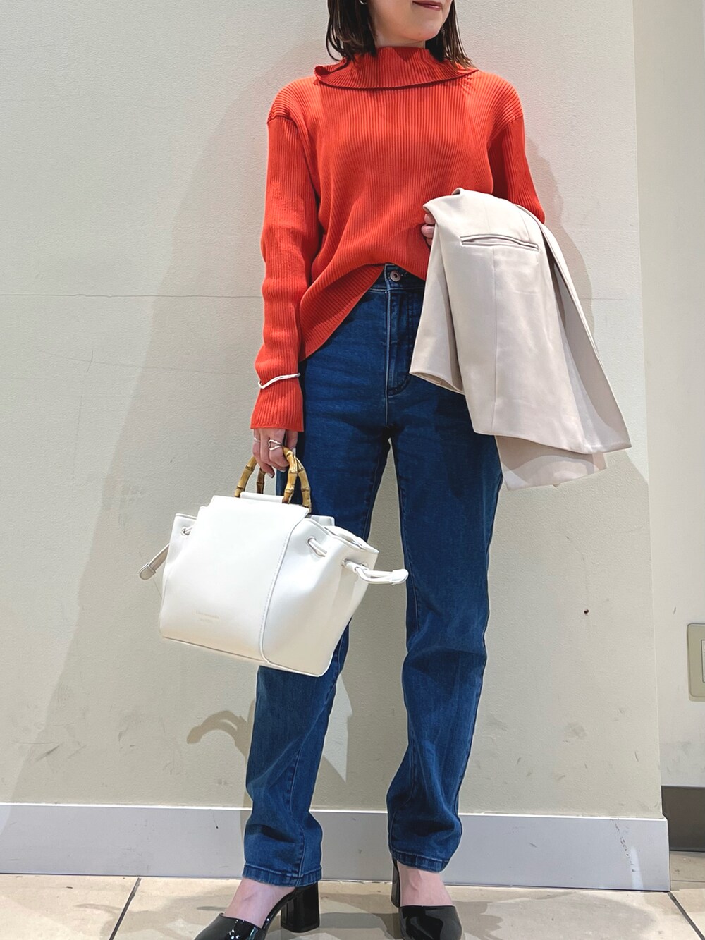 オレンジ系のカーディガン/ボレロ、ブルー系のデニムパンツ、ホワイト系のショルダーバッグを着用したレディースの春コーディネートの3枚目の写真