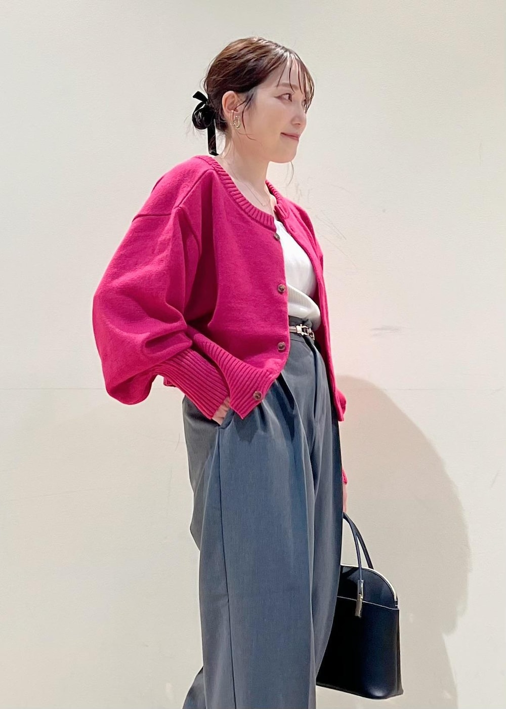 グレー系のタンクトップ、ブラック系のショルダーバッグ、ピンク系のカーディガン/ボレロを着用したレディースの秋コーディネートの2枚目の写真