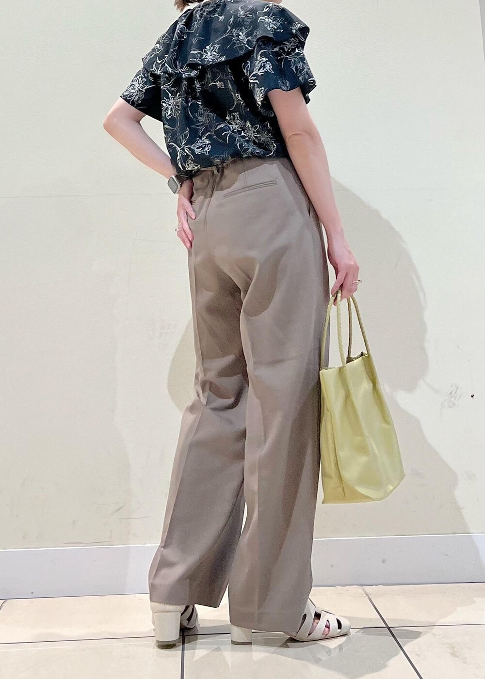 イエロー系のトートバッグ、ホワイト系のサンダル、ブラウン系のその他パンツを着用したレディースの夏コーディネートの2枚目の写真