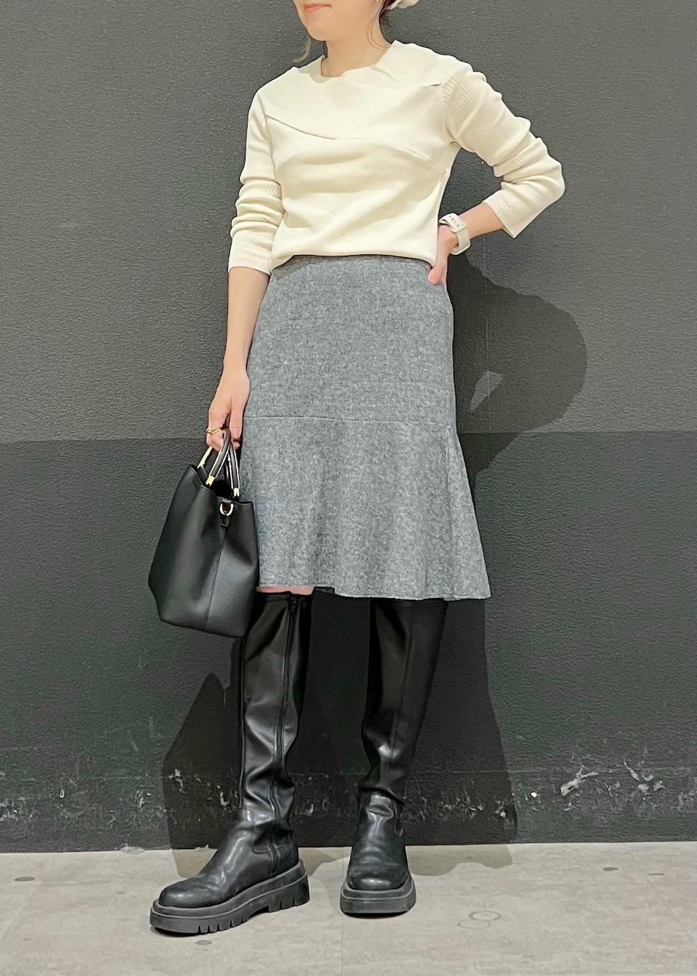 グレー系のスカート、ブラック系のショルダーバッグ、ホワイト系のニット/セーターを着用したレディースの秋コーディネートの3枚目の写真