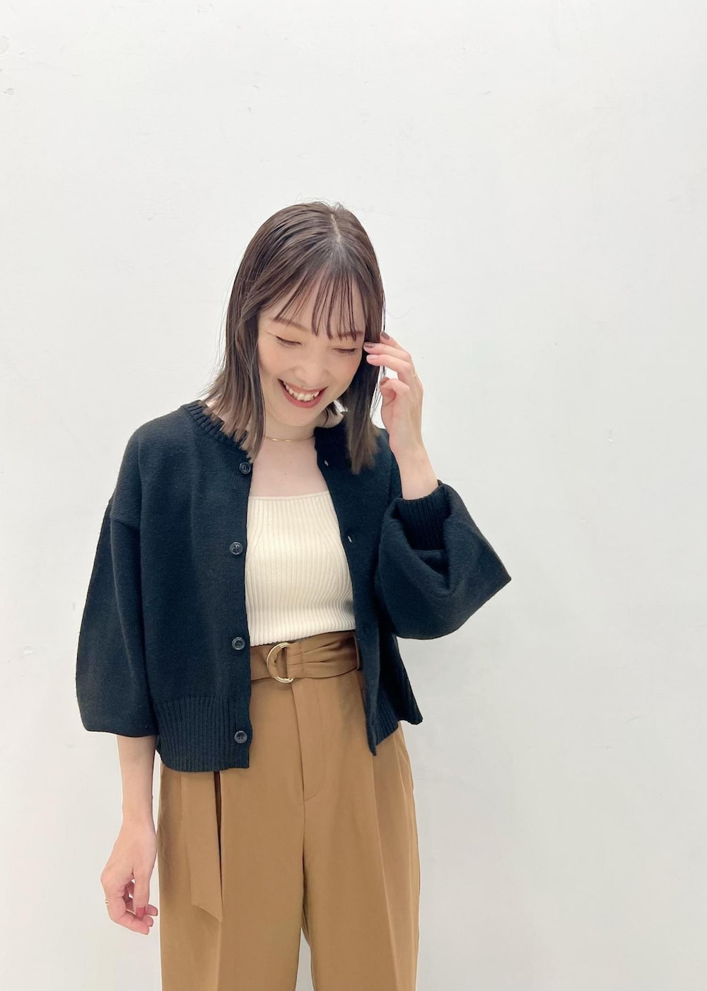 ブラック系のカーディガン/ボレロ、ホワイト系のベスト、ブラウン系のブーツを着用したレディースの秋コーディネートの4枚目の写真