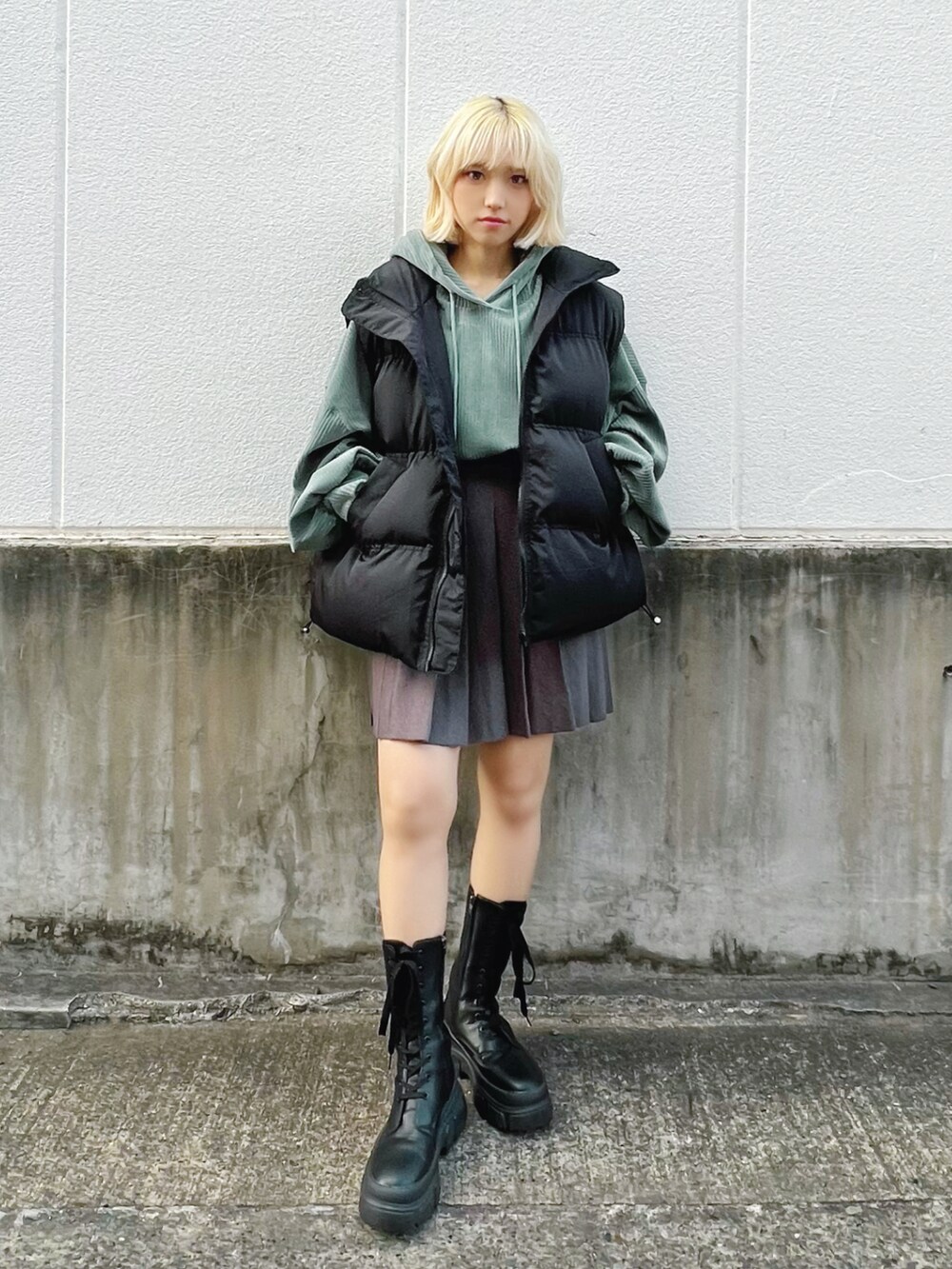 グリーン系のパーカー、グレー系のスカート、ブラック系のブーツを着用したレディースの冬コーディネートの2枚目の写真