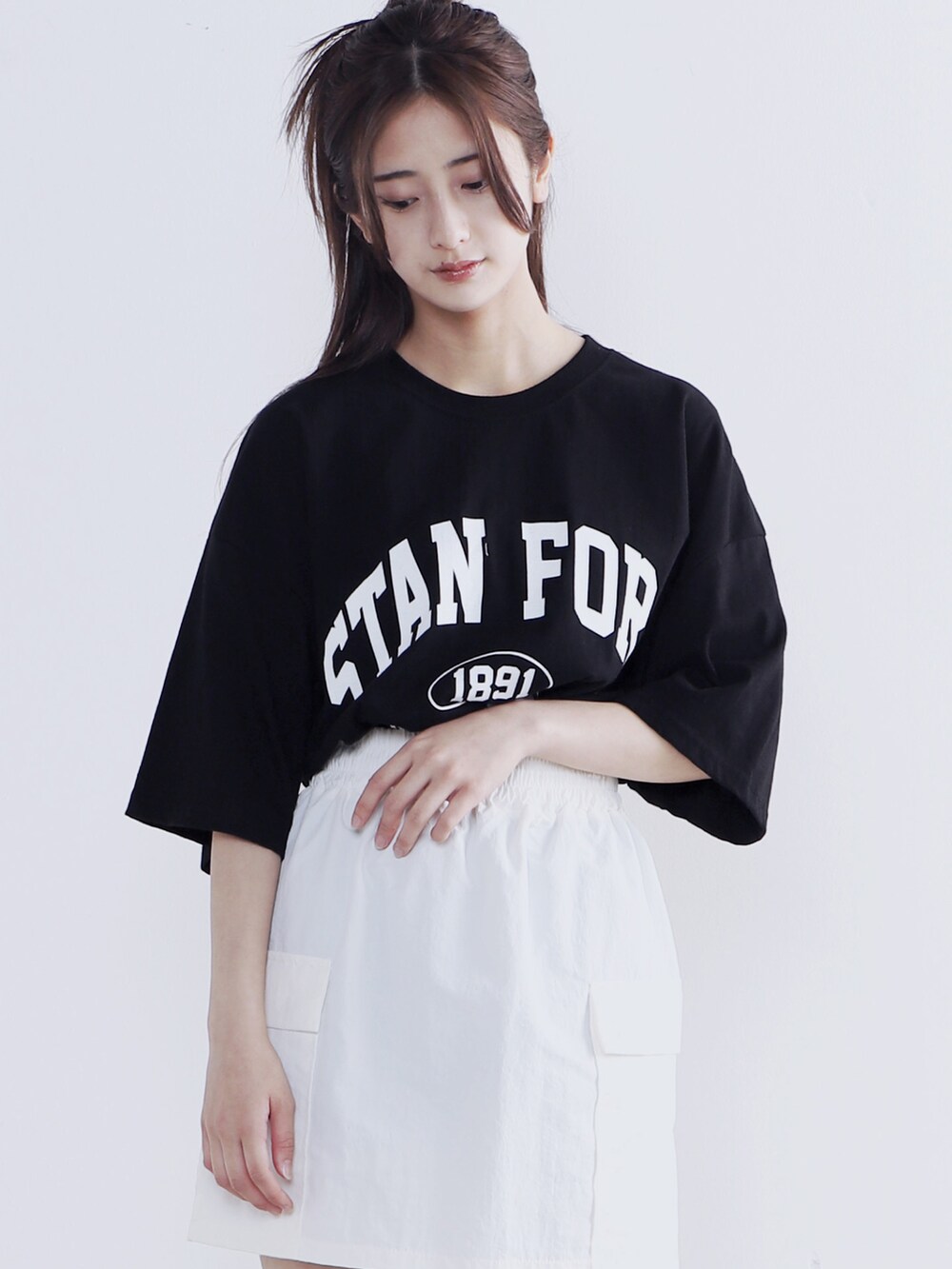 ブラック系のショルダーバッグ、ブラック系のTシャツ/カットソー、ホワイト系のスカートを着用したレディースの夏コーディネートの3枚目の写真