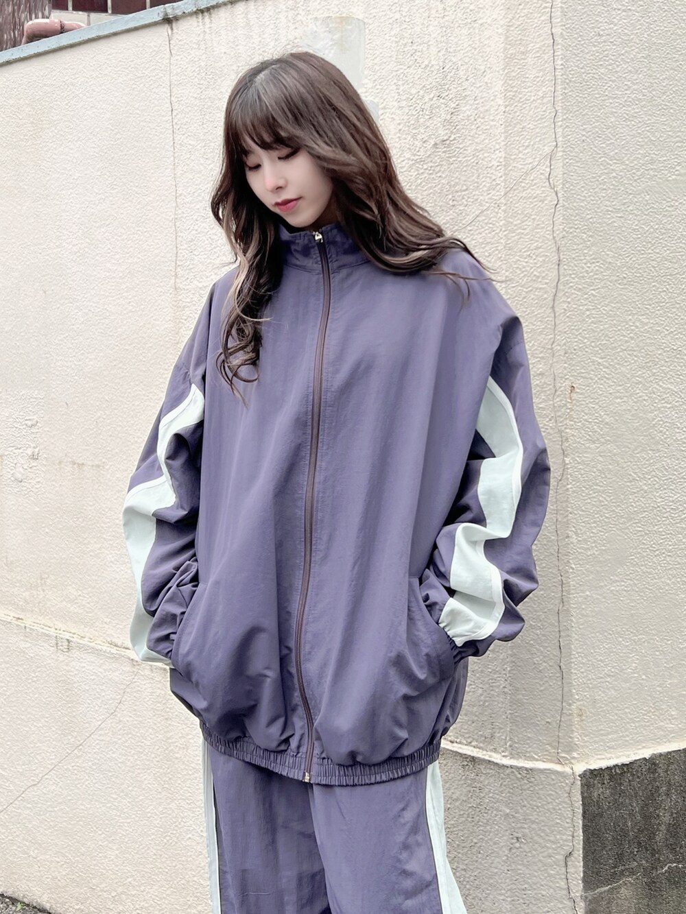 ホワイト系のスニーカー、パープル系のナイロンジャケット、パープル系のその他パンツを着用したレディースの冬コーディネートの2枚目の写真