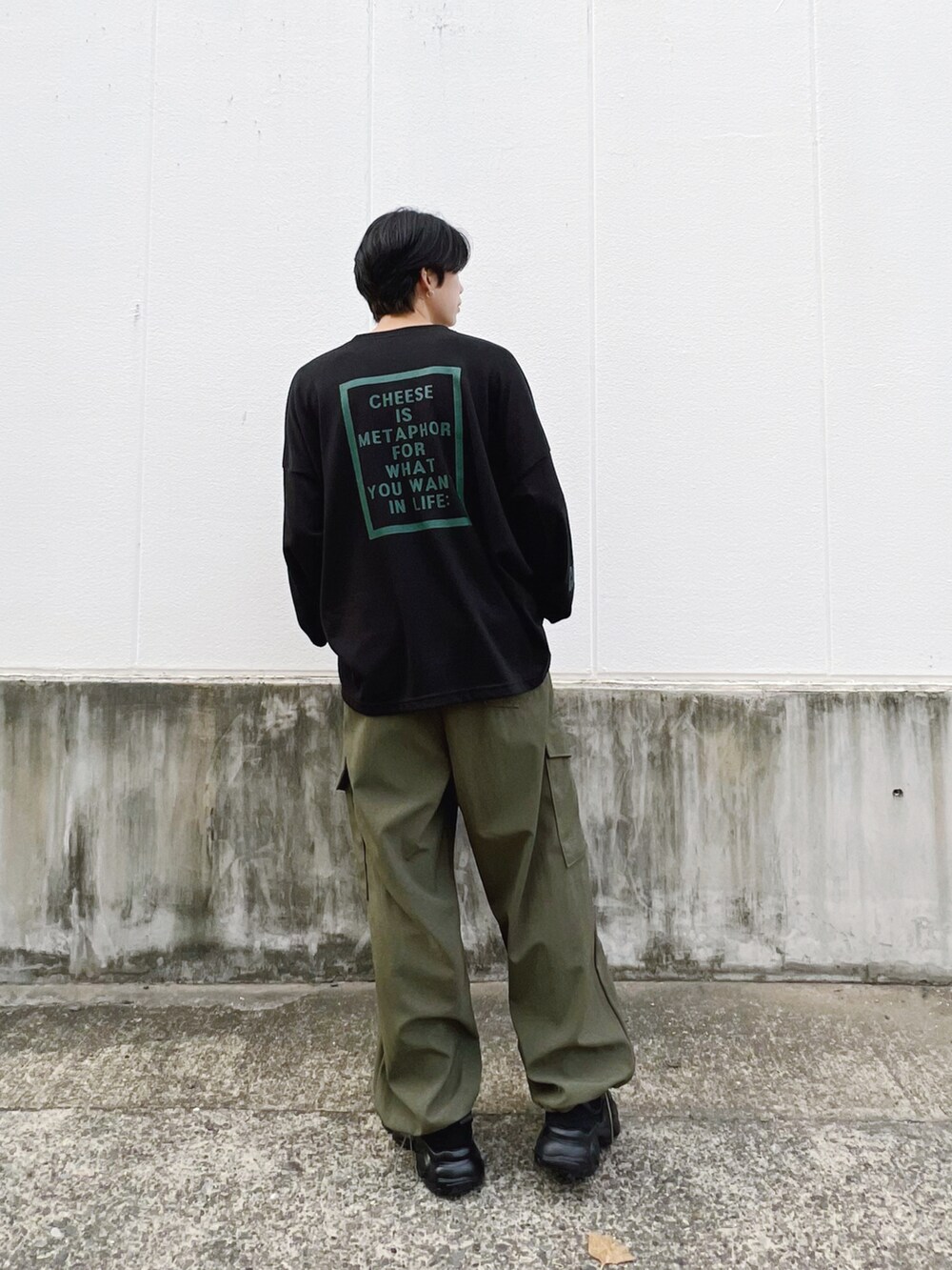 グリーン系のカーゴパンツ、ブラック系のTシャツ/カットソー、ブラック系のスニーカーを着用したメンズの秋コーディネートの3枚目の写真