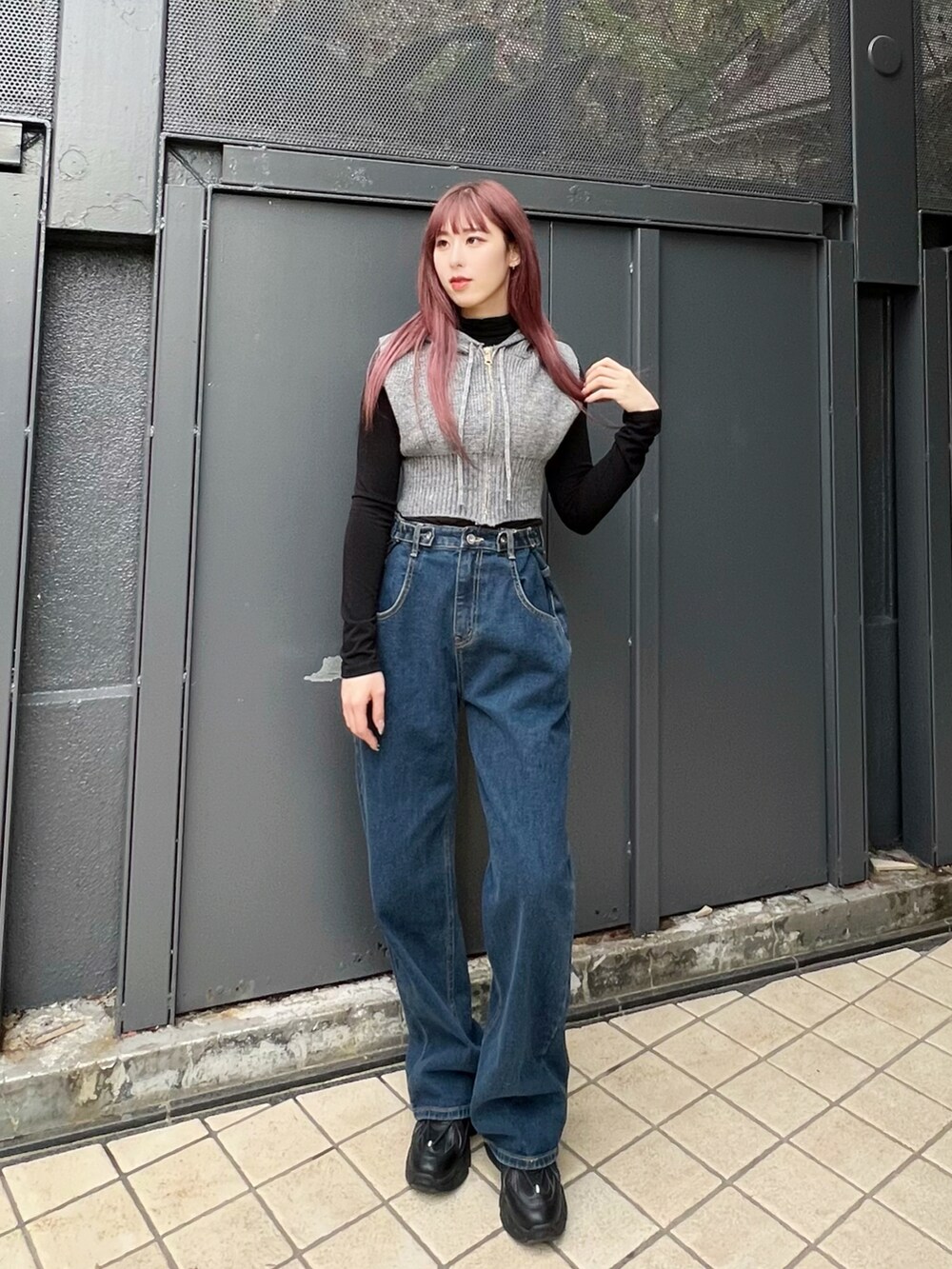 ブルー系のデニムパンツ、ブラック系のスニーカー、グレー系のベストを着用したレディースの冬コーディネートの4枚目の写真