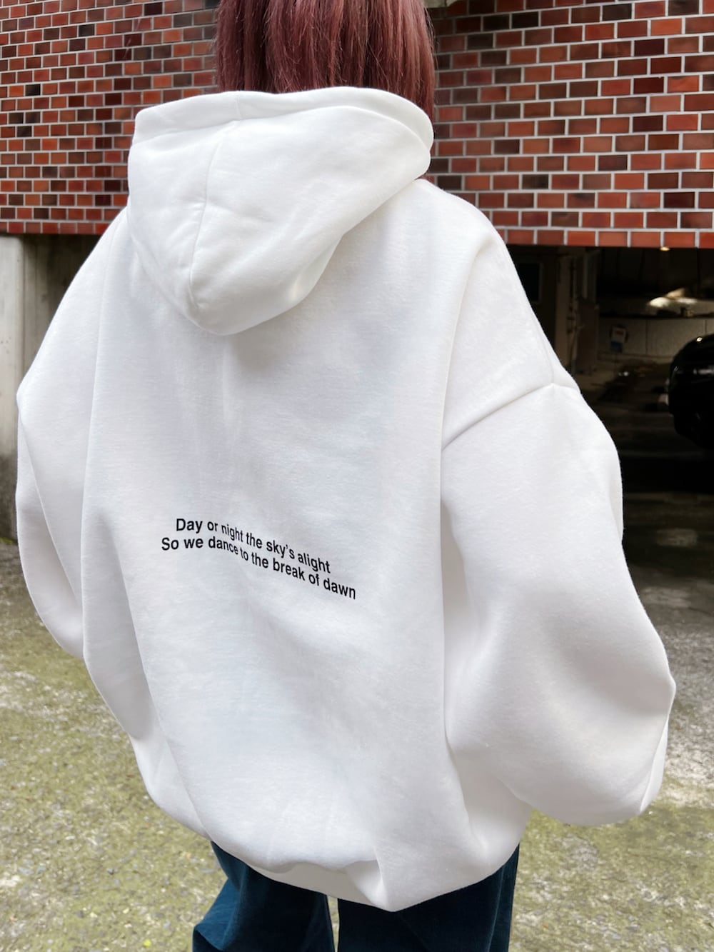 ブルー系のデニムパンツ、ブラック系のダウンベスト、ホワイト系のパーカーを着用したレディースの冬コーディネートの5枚目の写真