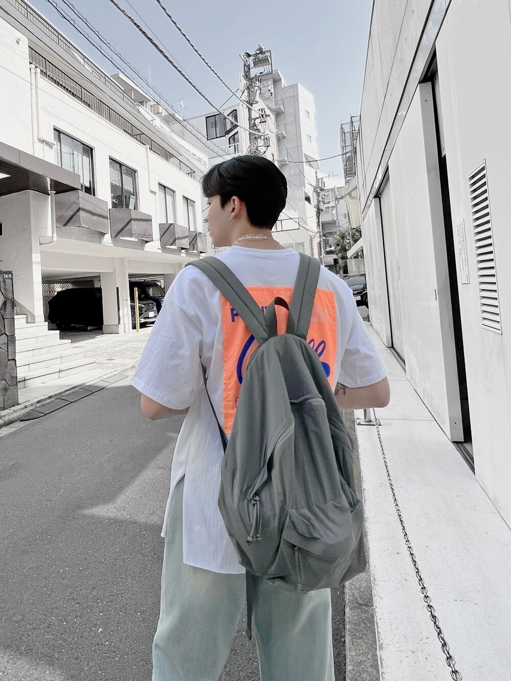 ブルー系のデニムパンツ、グレー系のバックパック/リュック、ホワイト系のTシャツ/カットソーを着用したメンズの春コーディネートの2枚目の写真