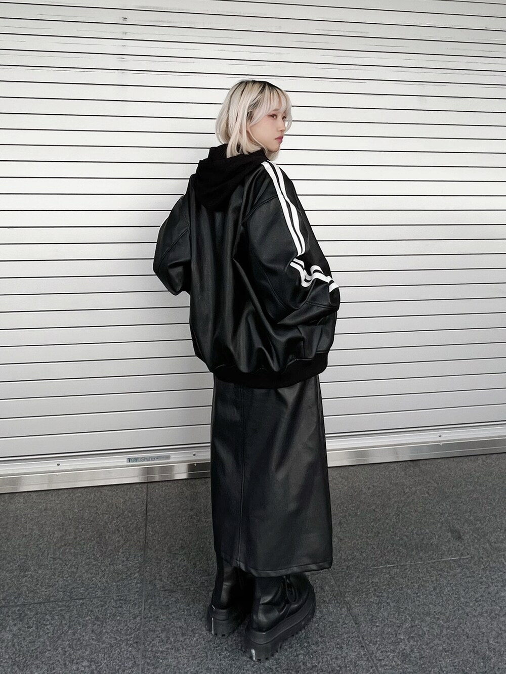 ブラック系のスカート、ブラック系のブーツ、ブラック系のブルゾンを着用したレディースの冬コーディネートの2枚目の写真