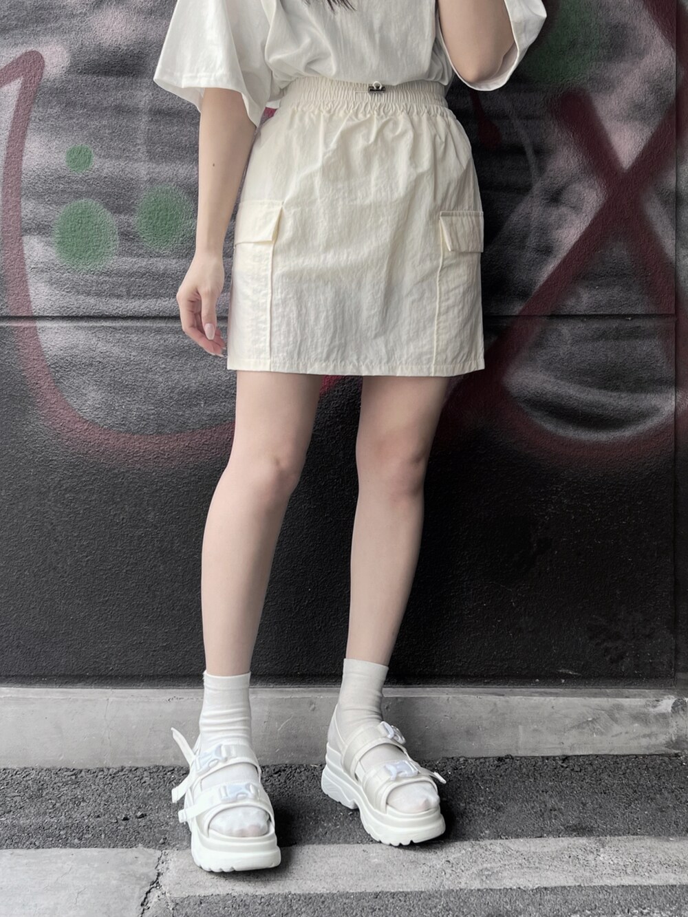 ホワイト系のサンダル、ホワイト系のスカート、ホワイト系のTシャツ/カットソーを着用したレディースの夏コーディネートの3枚目の写真