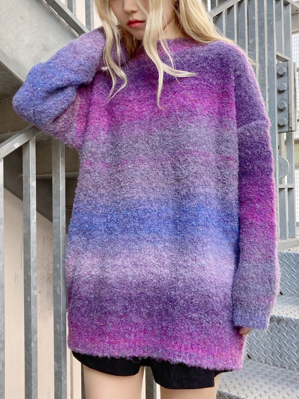 ブラック系のダウンジャケット/コート、ブラック系のブーツ、パープル系のニット/セーターを着用したレディースの冬コーディネートの2枚目の写真