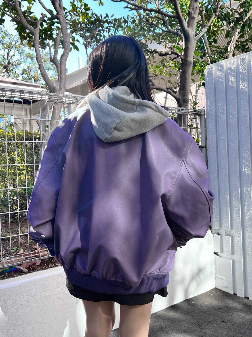 グレー系のパーカー、ブラック系のスカート、パープル系のライダースジャケットを着用したレディースの冬コーディネートの5枚目の写真