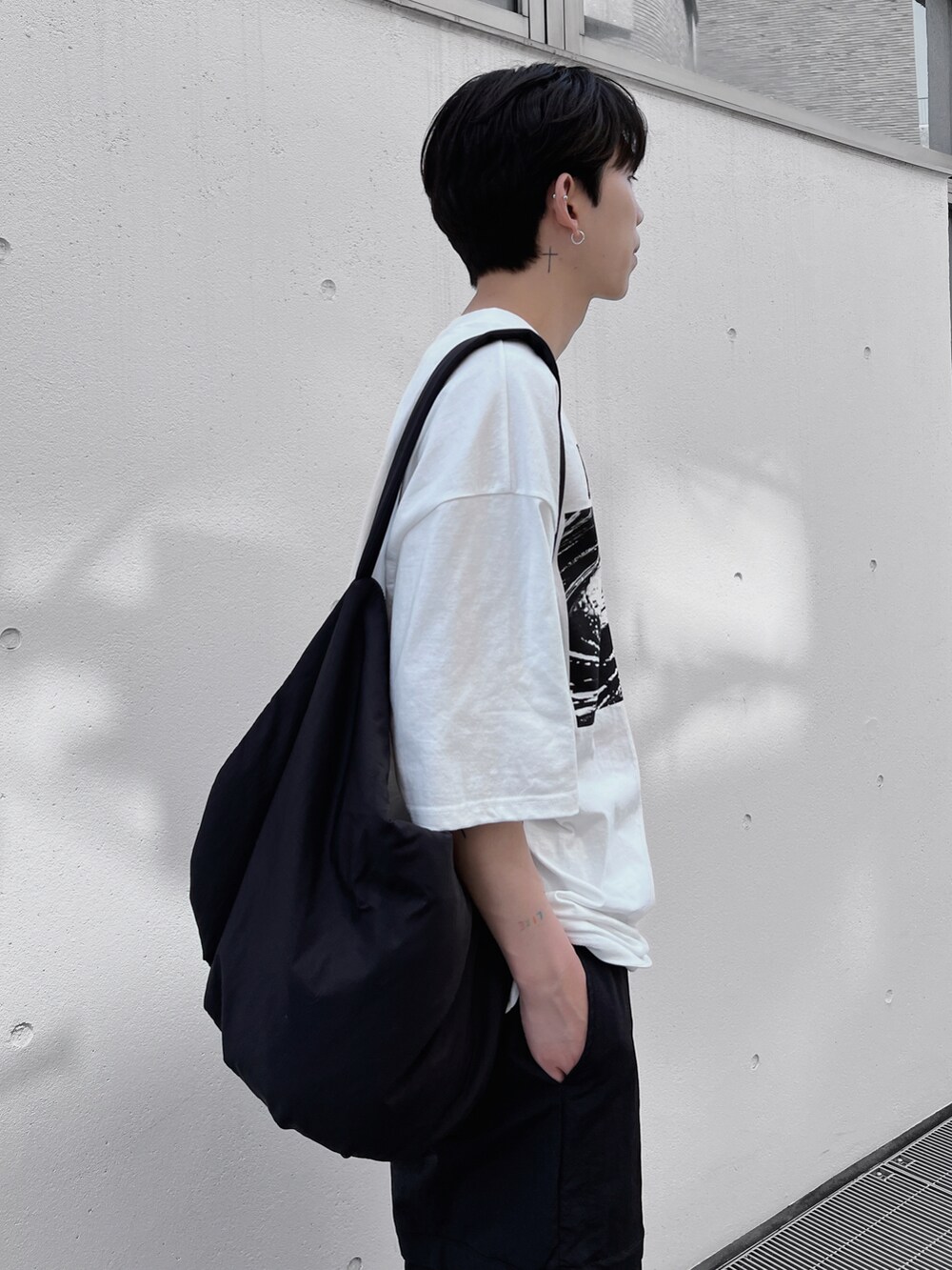 ブラック系のショルダーバッグ、ホワイト系のTシャツ/カットソー、ホワイト系のスニーカーを着用したメンズの春コーディネートの3枚目の写真