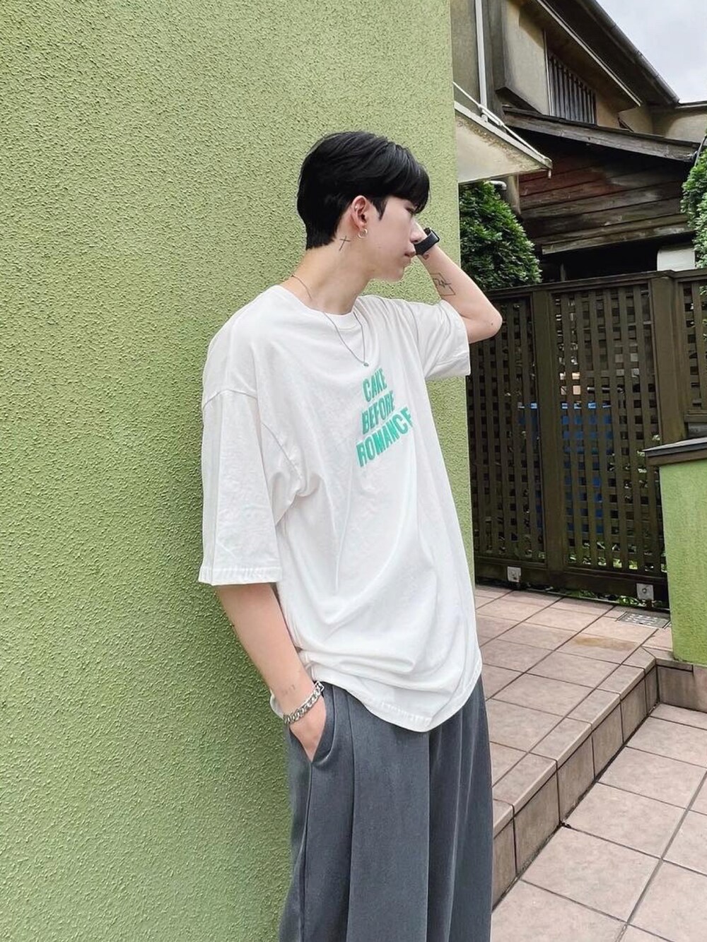 ホワイト系のTシャツ/カットソー、グレー系のスラックス、ブルー系のネックレスを着用したメンズの秋コーディネートの2枚目の写真