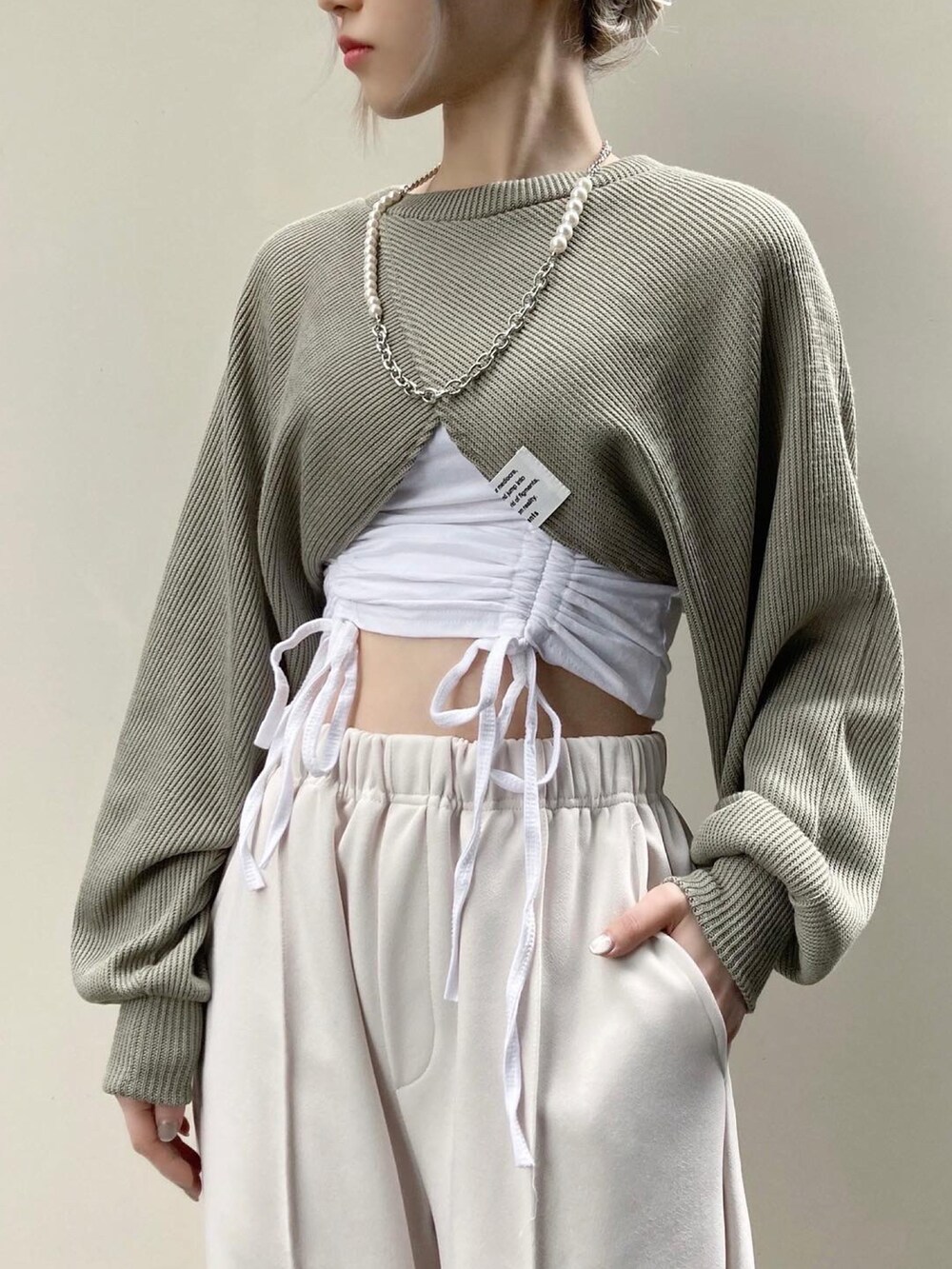ホワイト系のその他パンツ、グリーン系のニット/セーター、ホワイト系のキャミソールを着用したレディースの春コーディネートの2枚目の写真