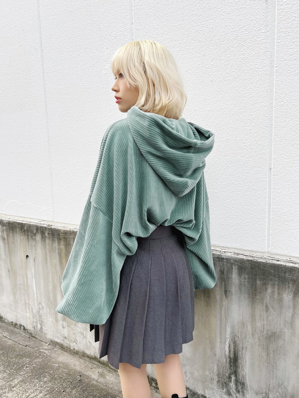 グリーン系のパーカー、グレー系のスカート、ブラック系のブーツを着用したレディースの冬コーディネートの5枚目の写真