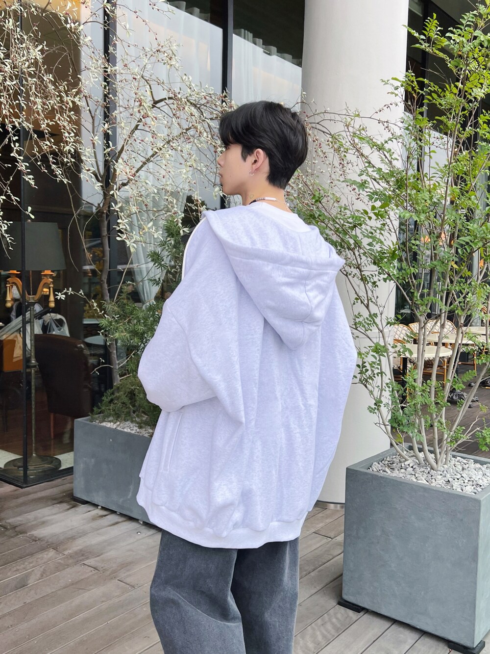 グレー系のパーカー、ブラック系のデニムパンツ、ブラック系のスニーカーを着用したメンズの冬コーディネートの3枚目の写真