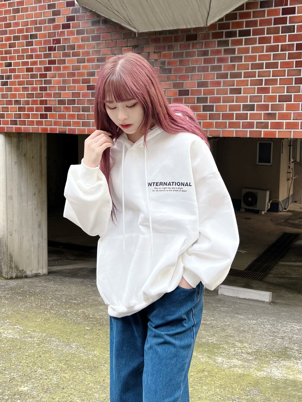 ブルー系のデニムパンツ、ブラック系のダウンベスト、ホワイト系のパーカーを着用したレディースの冬コーディネートの4枚目の写真