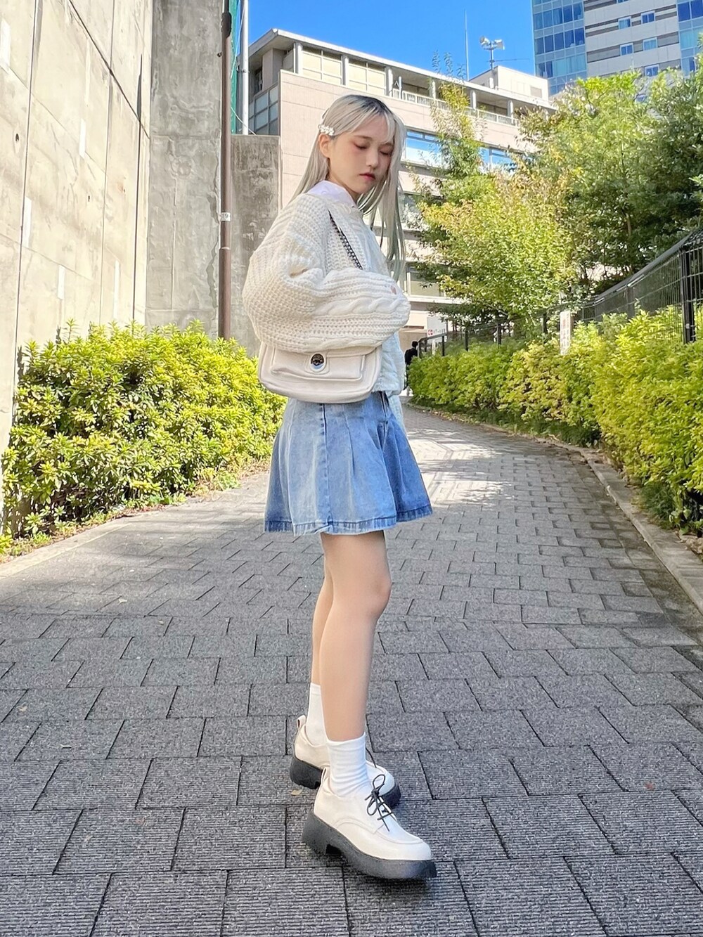 ホワイト系のシャツ/ブラウス、ホワイト系のニット/セーター、ブルー系のデニムスカートを着用したレディースの冬コーディネートの2枚目の写真