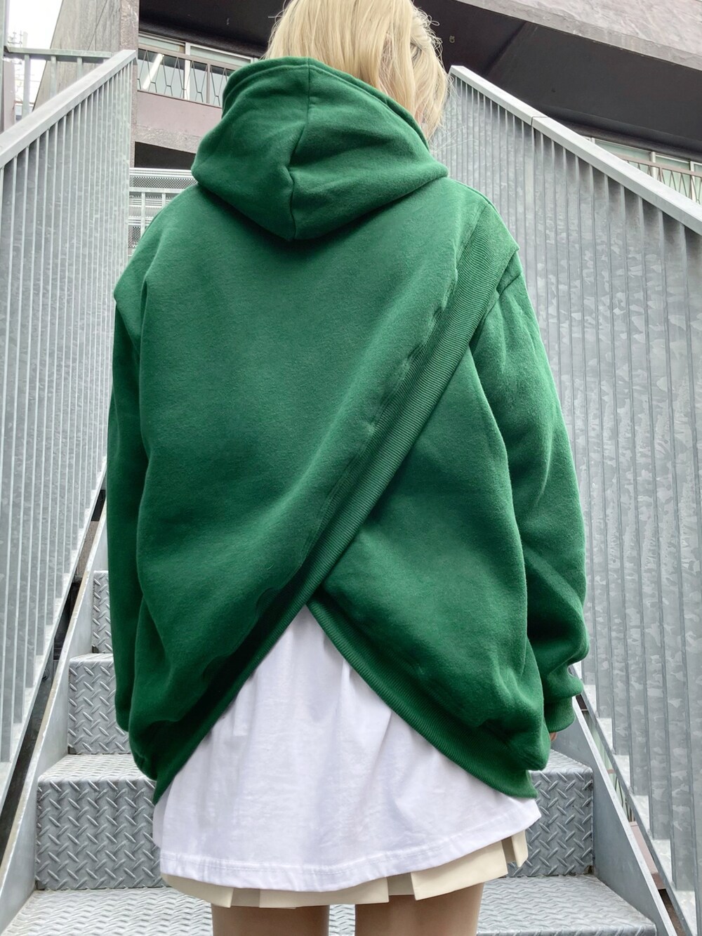 ホワイト系のスカート、グリーン系のパーカー、ホワイト系のスニーカーを着用したレディースの秋コーディネートの2枚目の写真