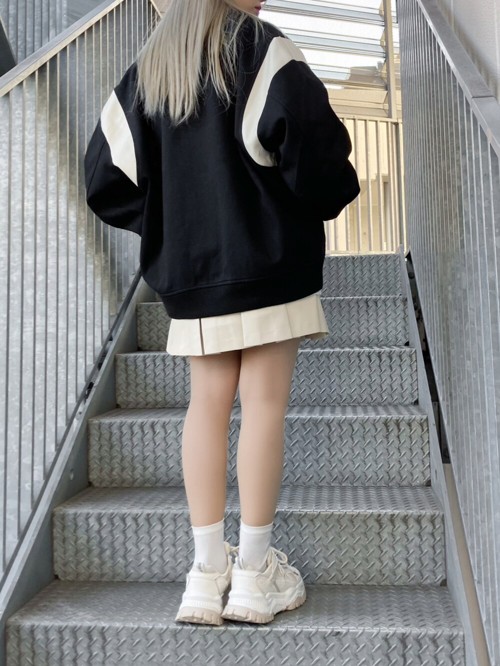 ホワイト系のスカート、ホワイト系のスニーカー、ブラック系のスタジャンを着用したレディースの冬コーディネートの2枚目の写真