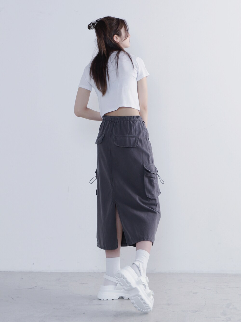 ブラック系のスカート、ホワイト系のTシャツ/カットソー、ホワイト系のサンダルを着用したレディースの夏コーディネートの2枚目の写真