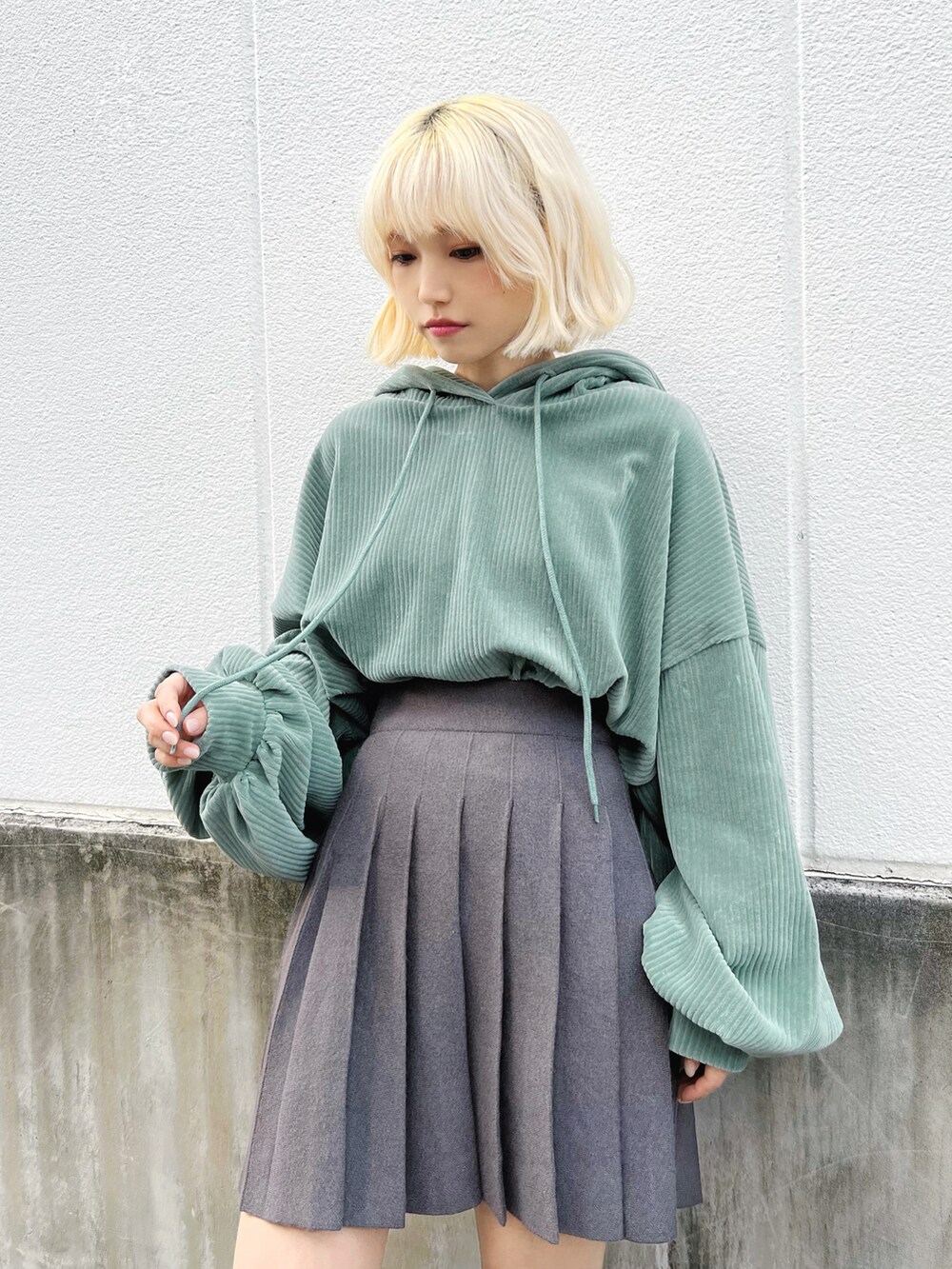 グリーン系のパーカー、グレー系のスカート、ブラック系のブーツを着用したレディースの冬コーディネートの4枚目の写真