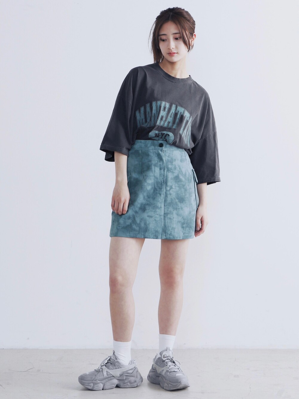 グレー系のTシャツ/カットソー、ブルー系のスカート、グレー系のスニーカーを着用したレディースの夏コーディネートの2枚目の写真