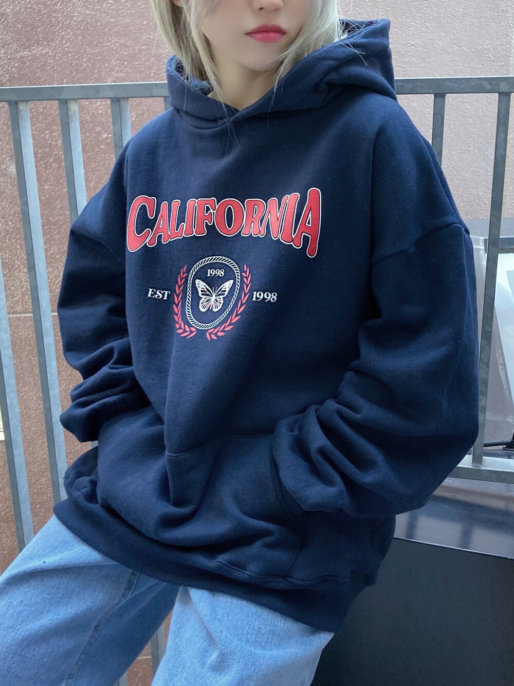 ブルー系のパーカー、ブルー系のデニムパンツ、ホワイト系のスニーカーを着用したレディースの春コーディネートの2枚目の写真