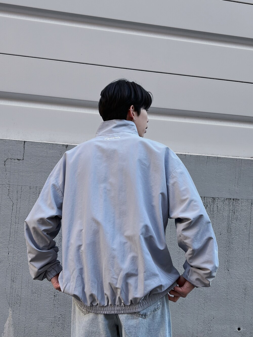 ブルー系のナイロンジャケット、ブルー系のデニムパンツ、ホワイト系のスニーカーを着用したメンズの春コーディネートの4枚目の写真