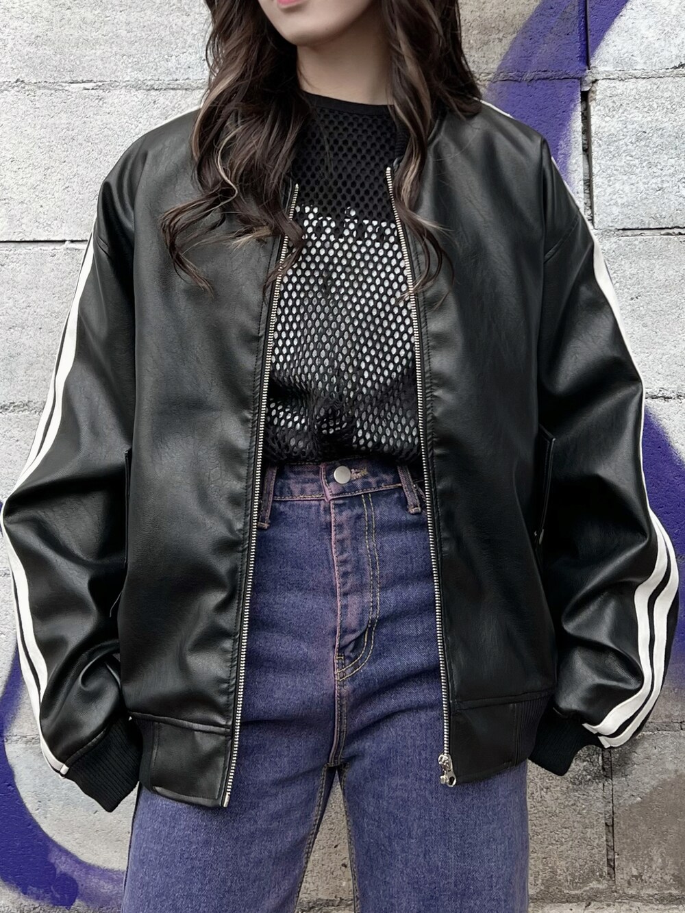 パープル系のデニムパンツ、ブラック系のTシャツ/カットソー、ブラック系のブルゾンを着用したレディースの冬コーディネートの3枚目の写真