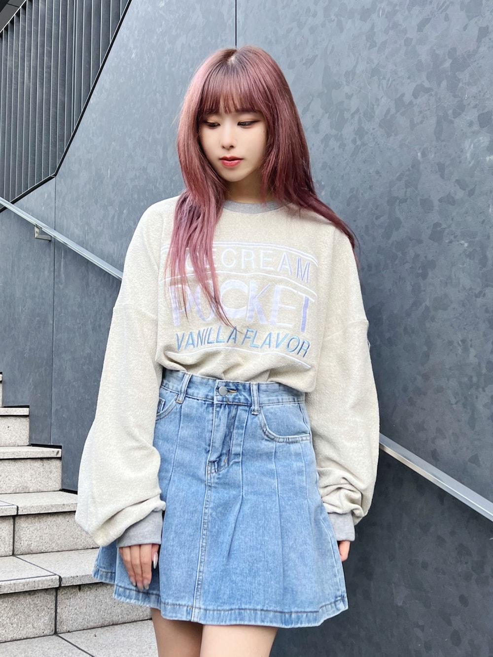 グリーン系のダウンベスト、グレー系のスウェット、ブルー系のデニムスカートを着用したレディースの冬コーディネートの4枚目の写真