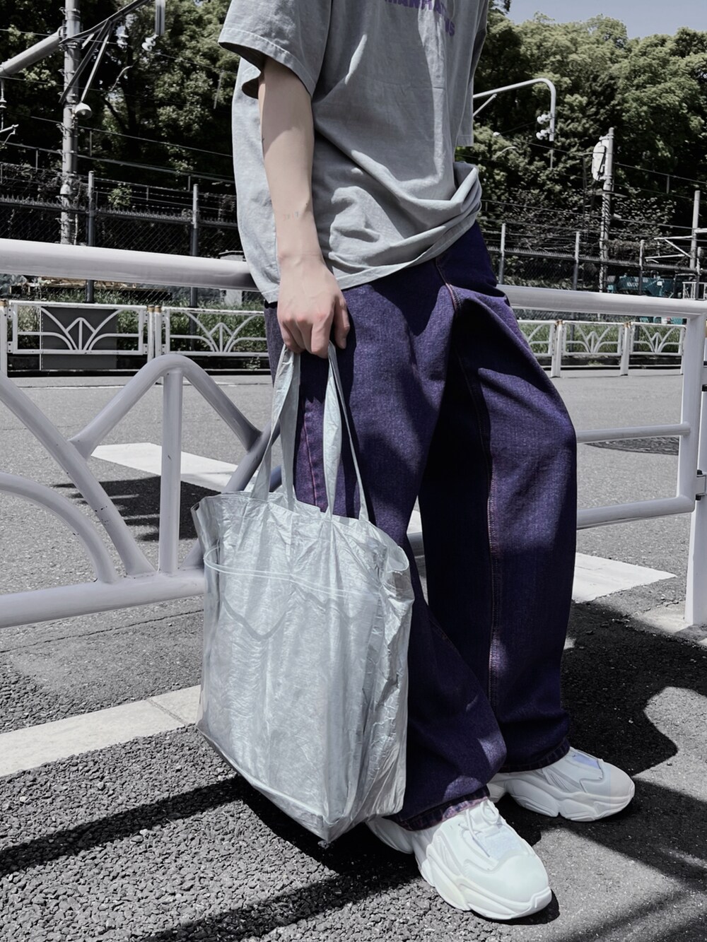 パープル系のデニムパンツ、ホワイト系のスニーカー、シルバー系のショルダーバッグを着用したレディースの春コーディネートの3枚目の写真