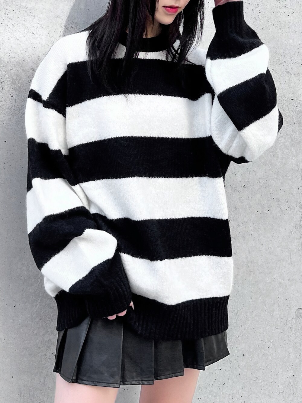 ブラック系のスカート、ブラック系のブーツ、ホワイト系のニット/セーターを着用したレディースの秋コーディネートの2枚目の写真